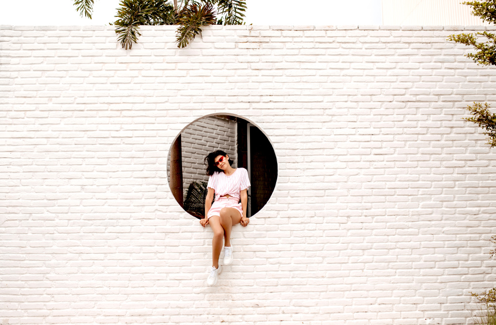 stunning-young-woman-sitting-bricked-wall-outdoor-shot-adorable-girl-sunglasses-posing-urban-background.jpg